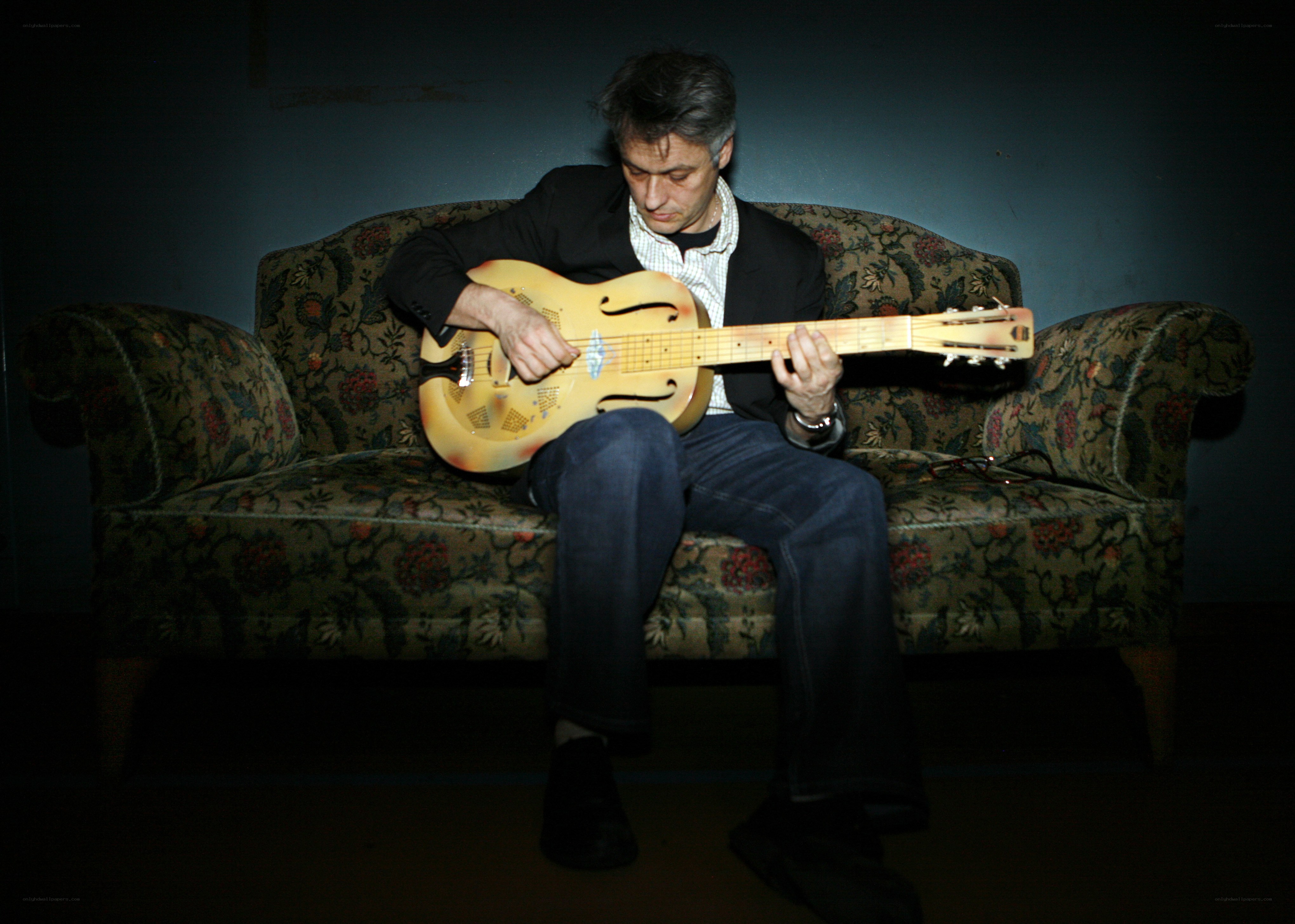 Man playing resonator guitar on couch