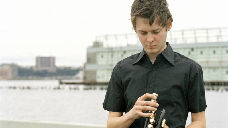 man playing trumpet by water