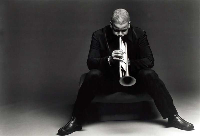man playing trumpet in black suit