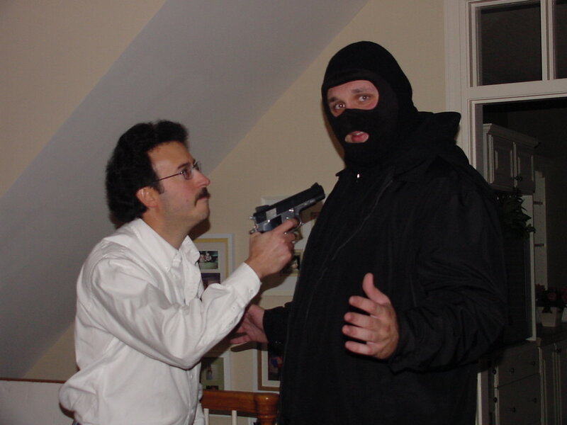 Man pointing gun at masked person