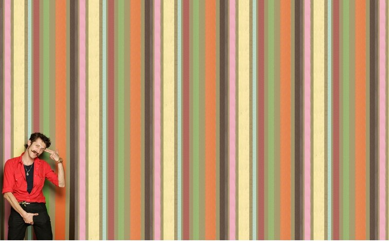 man posing in front of striped wall
