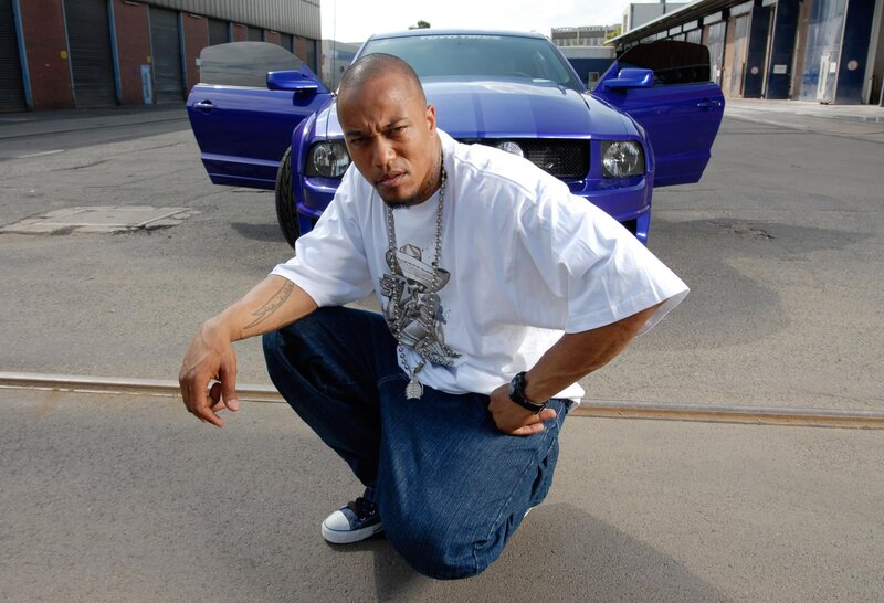 man posing with blue car