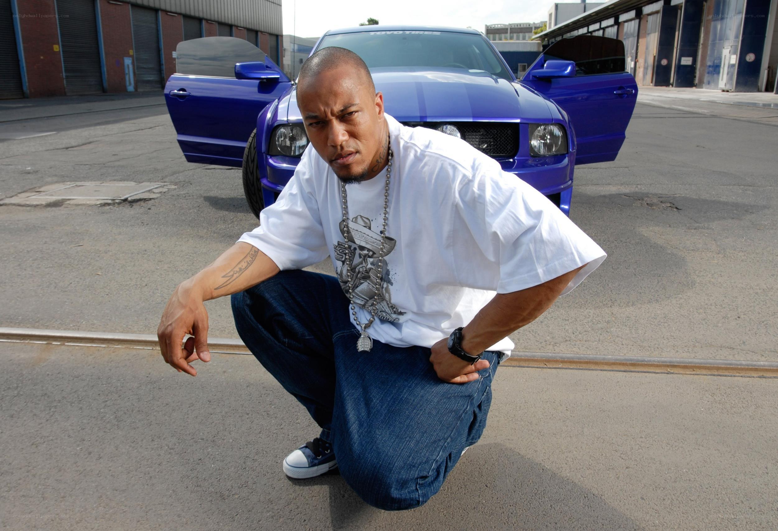 man posing with blue car