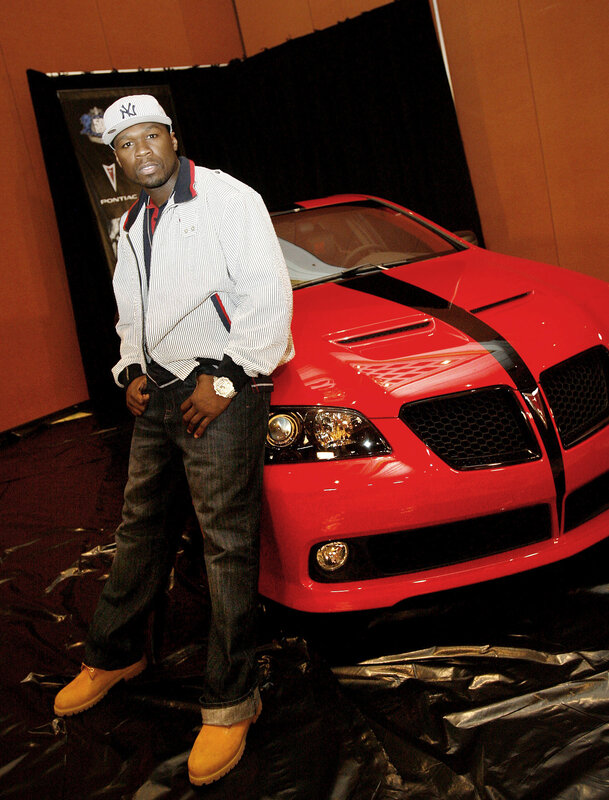 man posing with red car