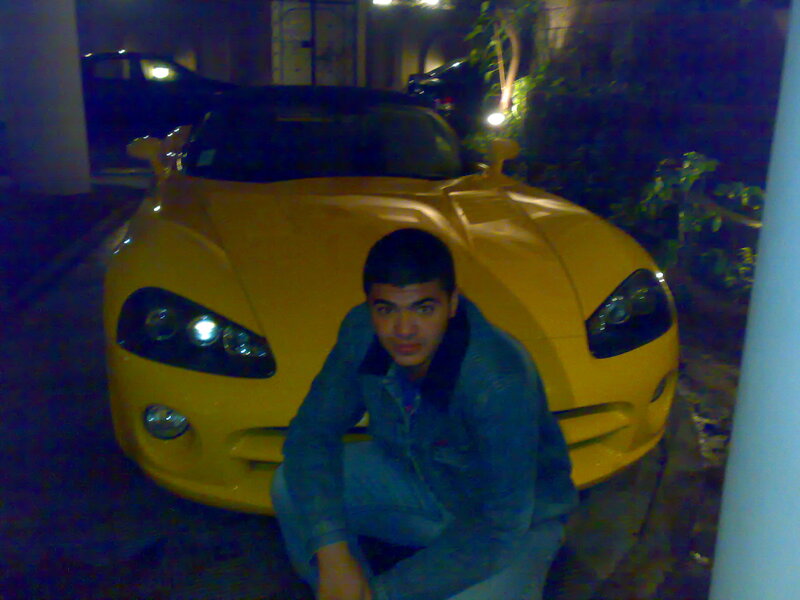man posing with yellow car