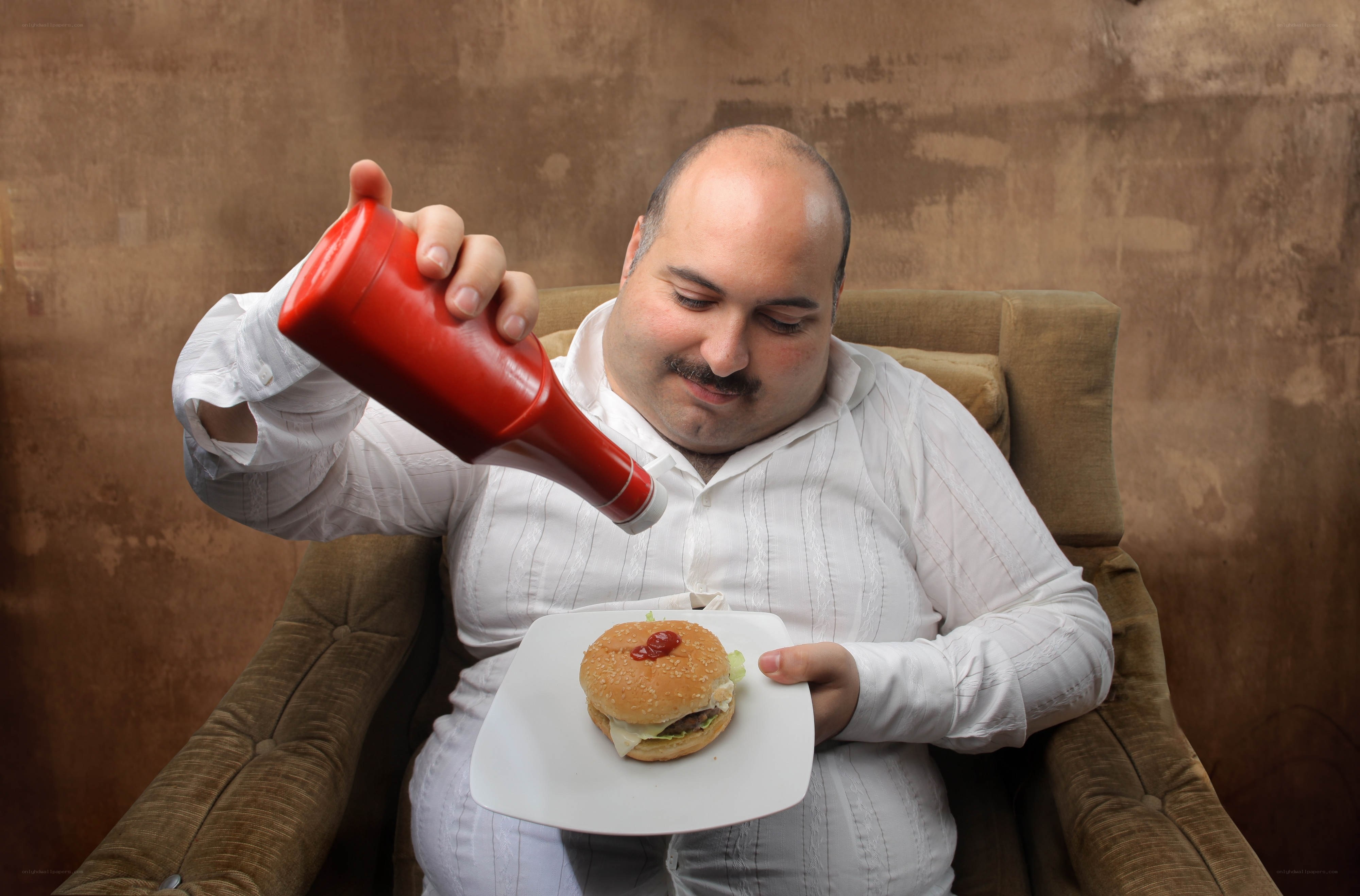 Man pouring ketchup on a burger