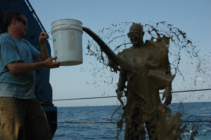 Man pouring mud on statue