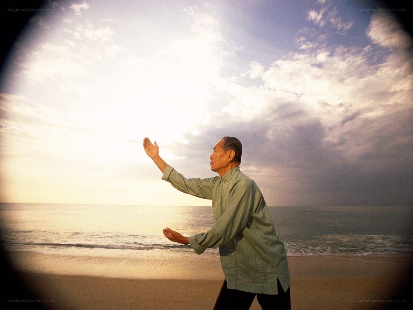 man practicing tai chi on beach