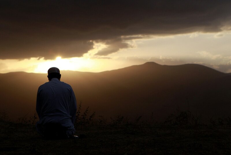 Man praying at sunset