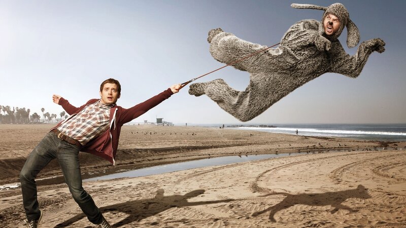Man pulling costumed person on beach
