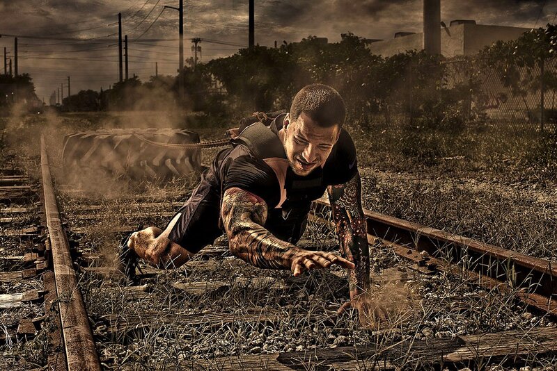 man pulling tire on train tracks