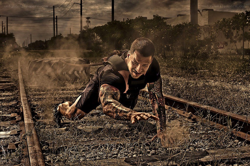 man pulling tire on train tracks