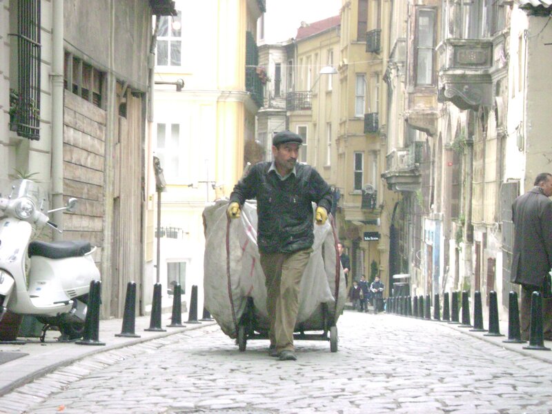 Man pushing cart on cobblestone street