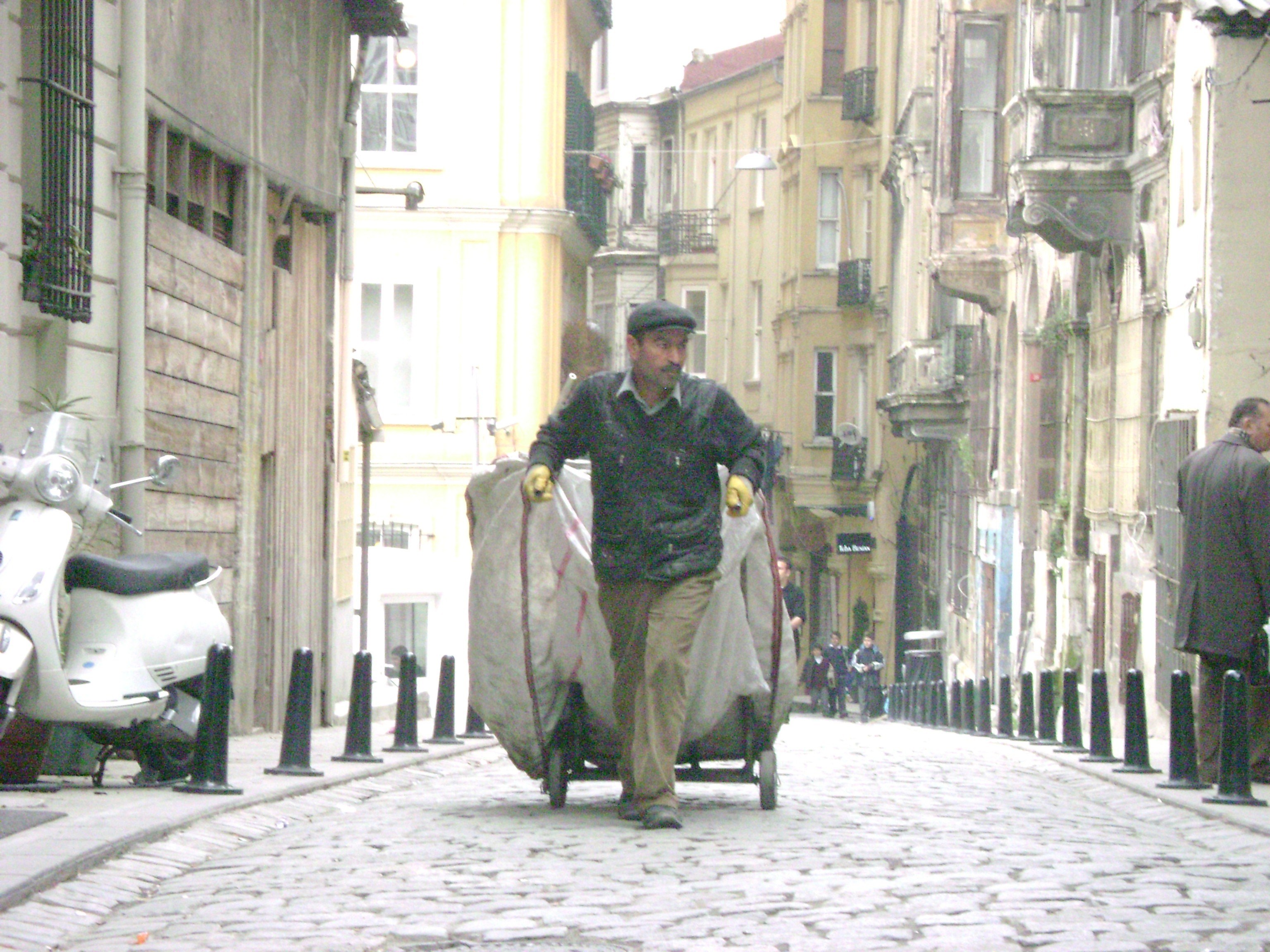 Man pushing cart on cobblestone street
