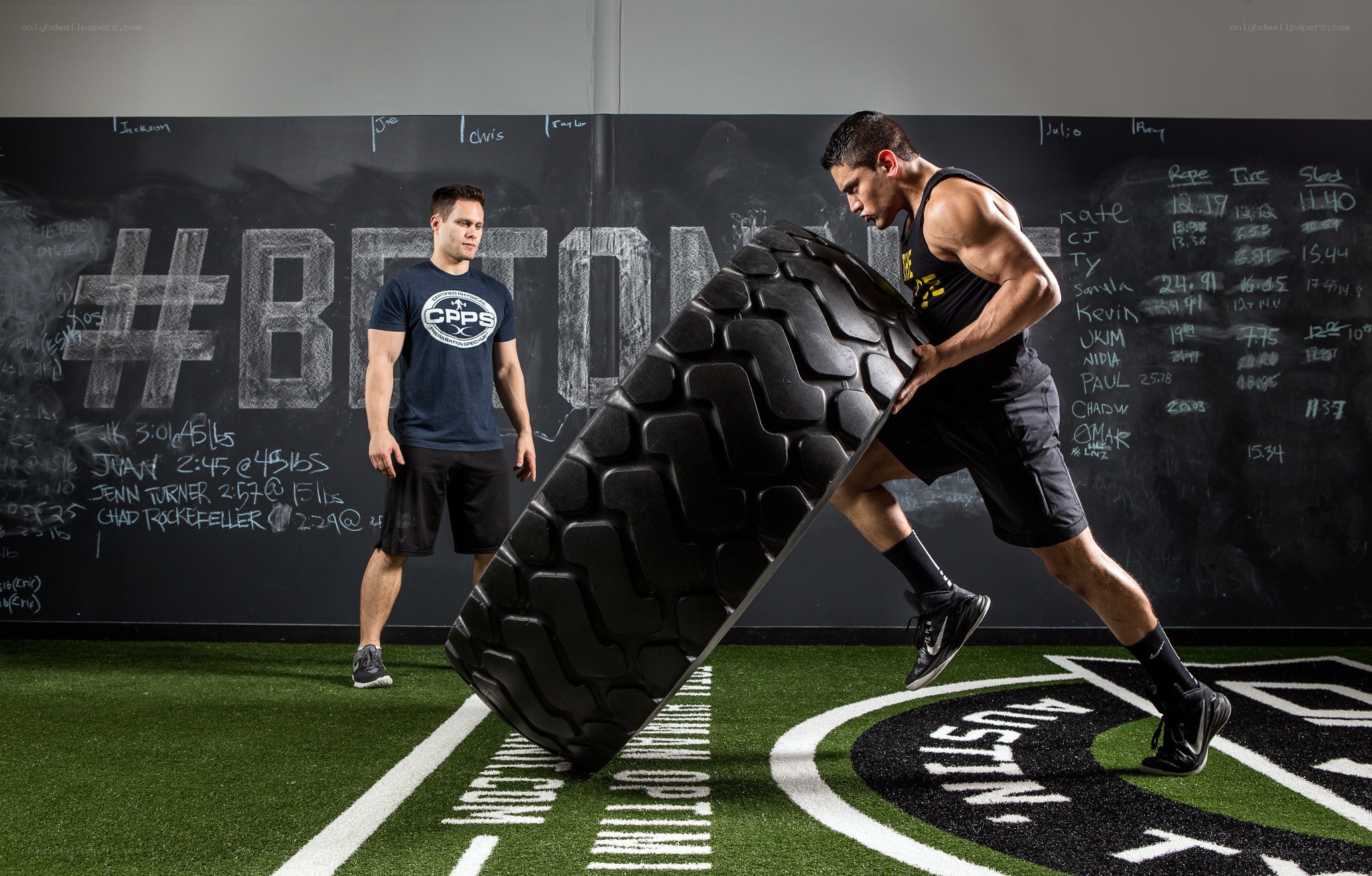 Man pushing large tire in gym