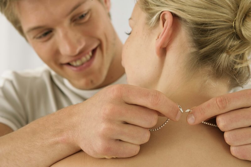 Man putting necklace on woman