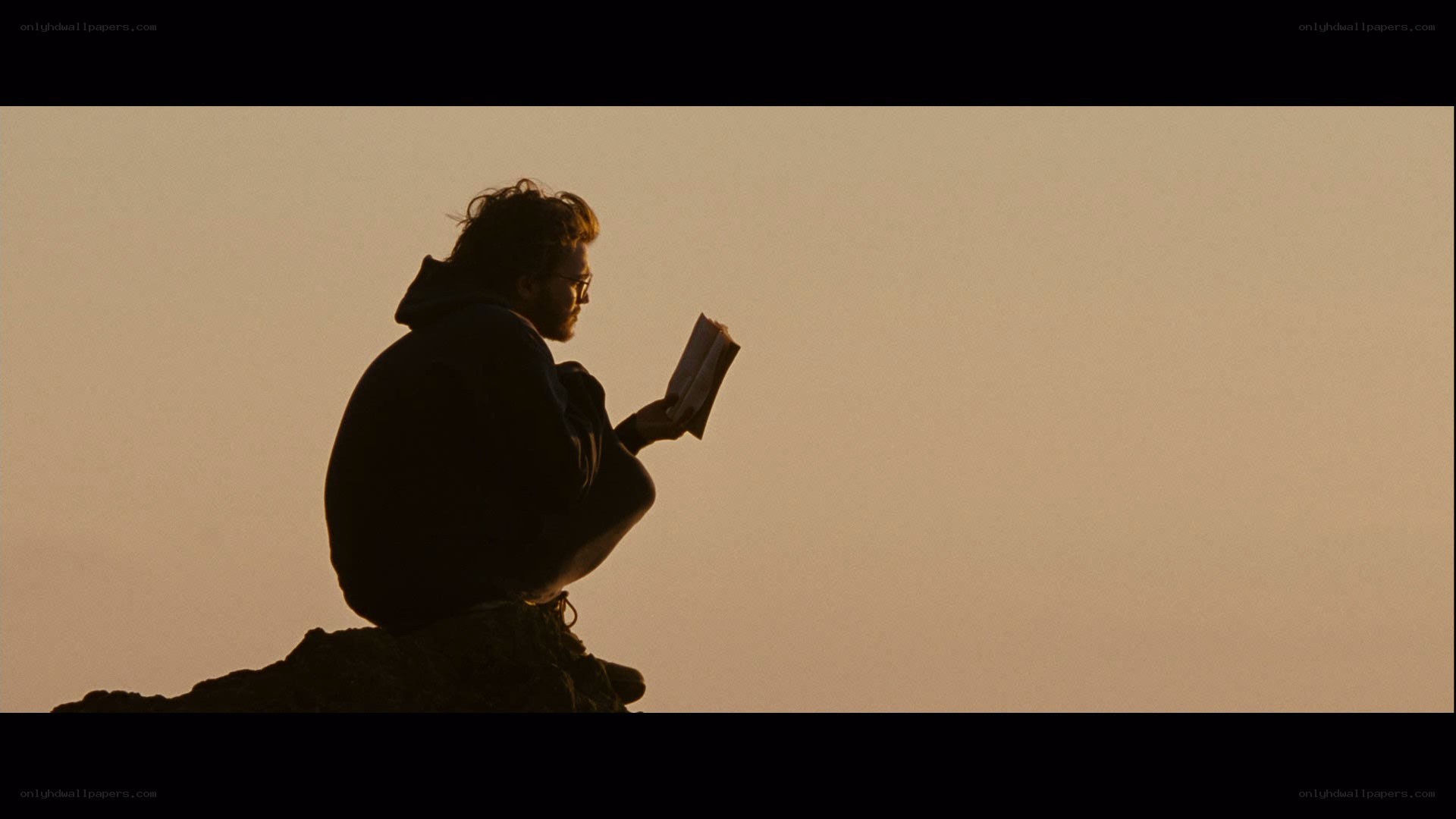 man reading book at sunset