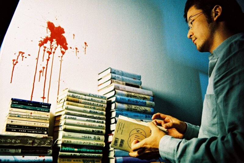 Man reading book near blood splatter