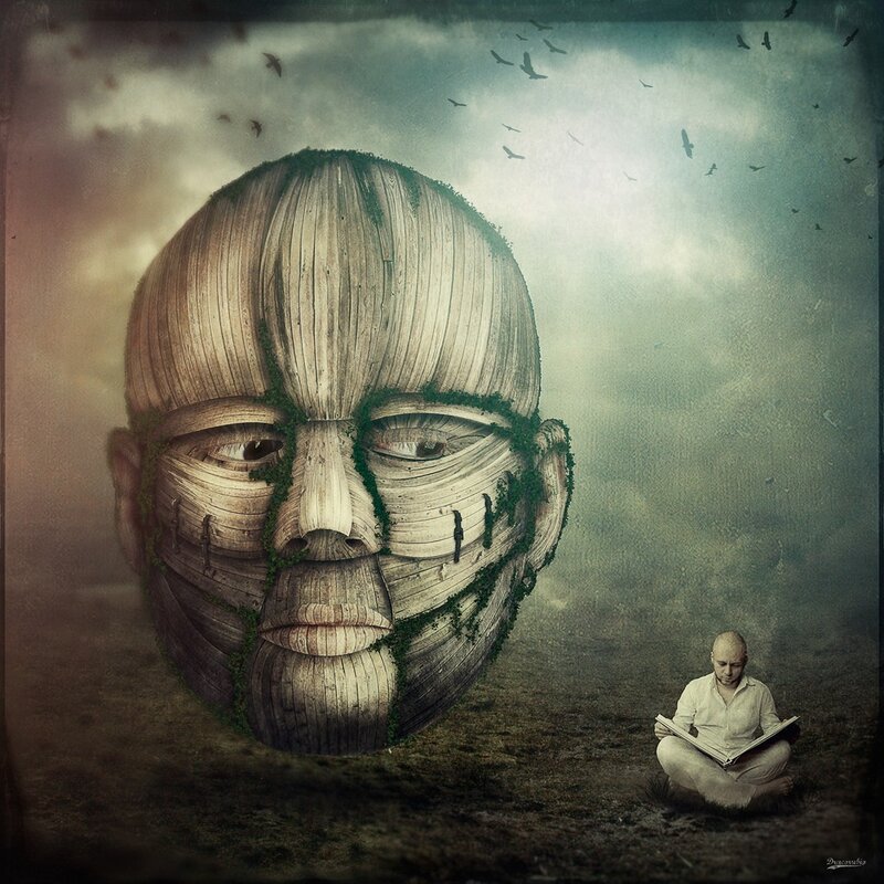 Man reading near giant wooden face