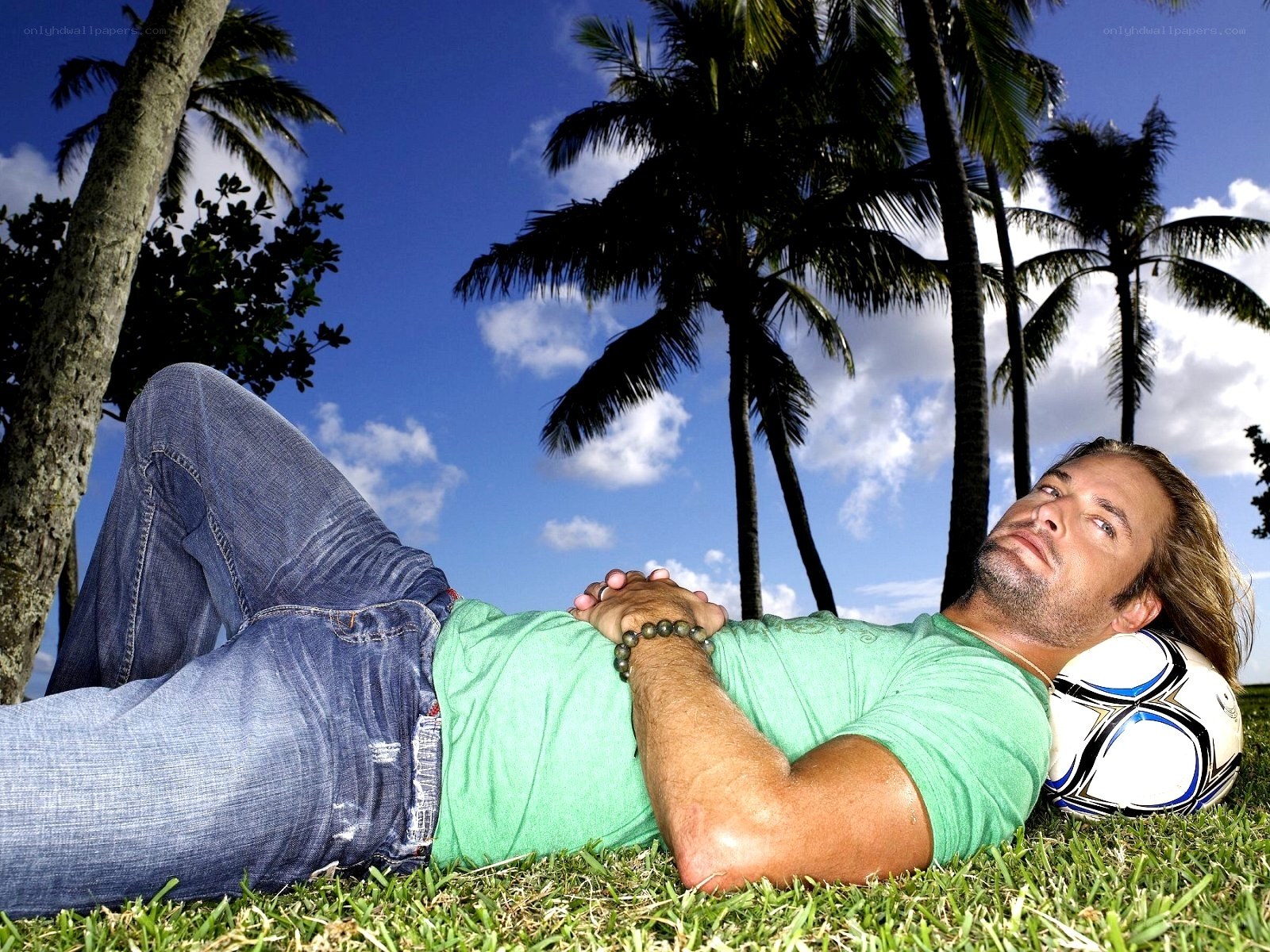 Man resting on grass with soccer ball
