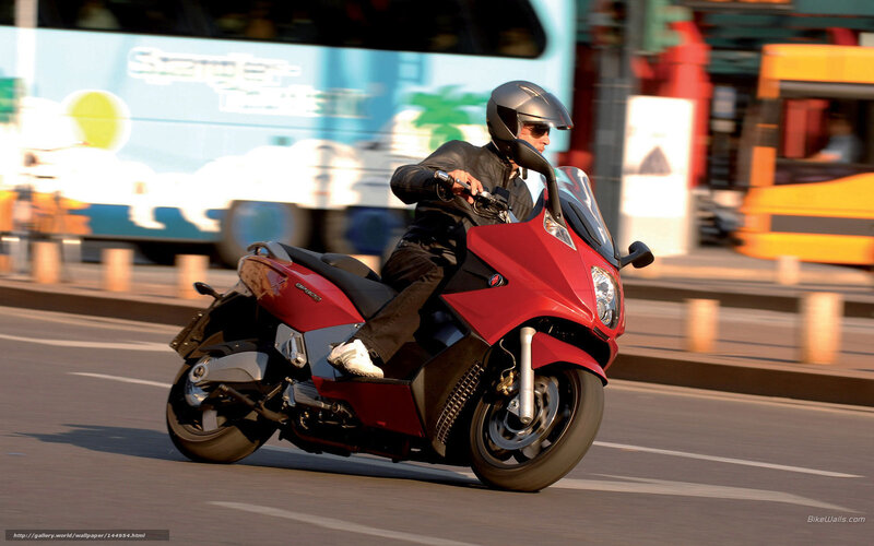Man riding red scooter on city street