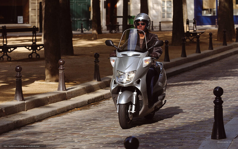 Man riding scooter on cobblestone street
