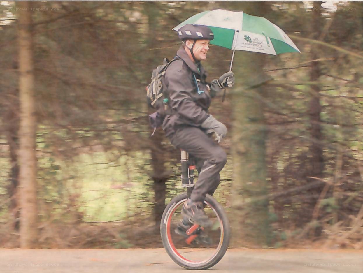 Man riding unicycle with umbrella
