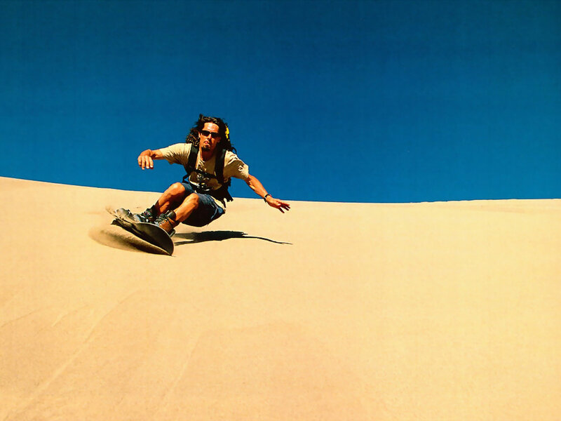 Man sandboarding on a dune