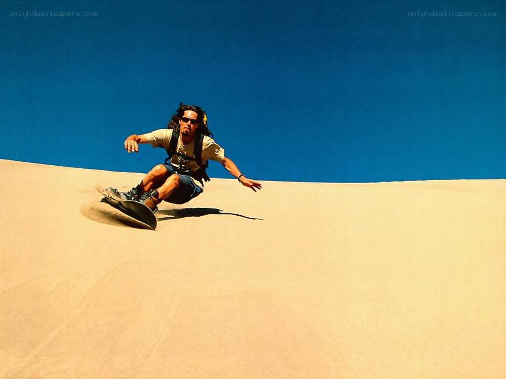 Man sandboarding on a dune