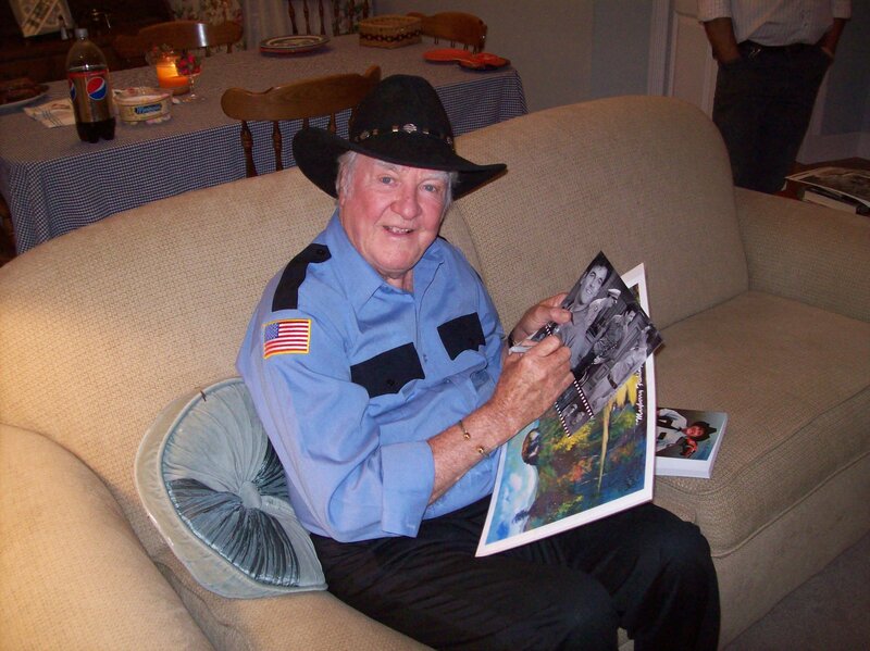 man signing photos on couch