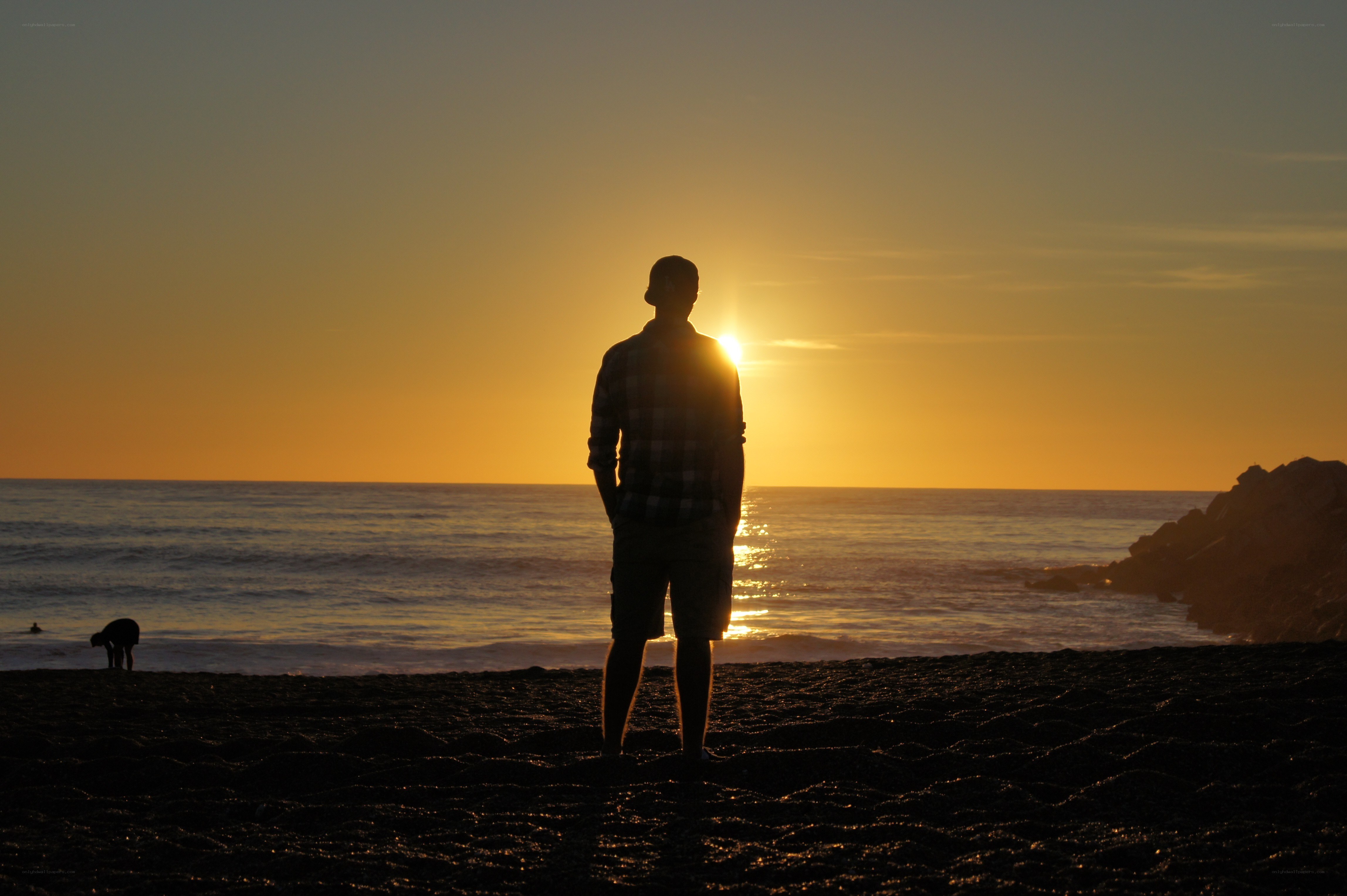 Man silhouetted at sunset on beach