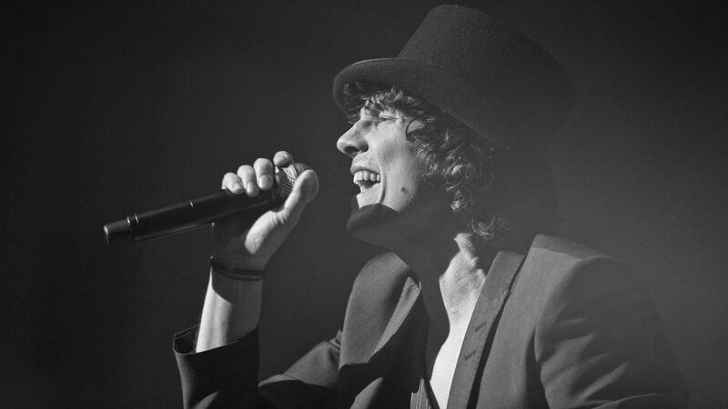 Man Singing into Microphone — Black, Dramatic, Night, Photograph, Hat, Suit