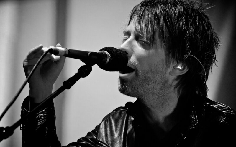 Man Singing into Microphone — Black, Intense, Photograph, Leather Jacket, Earpiece