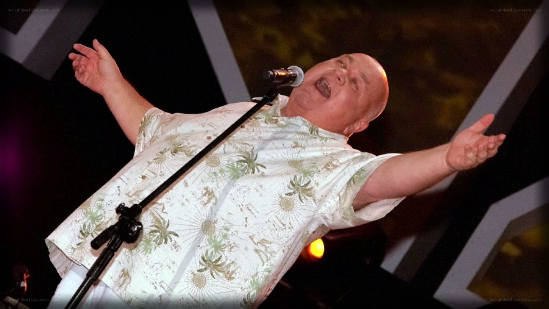 Man singing on stage with arms outstretched