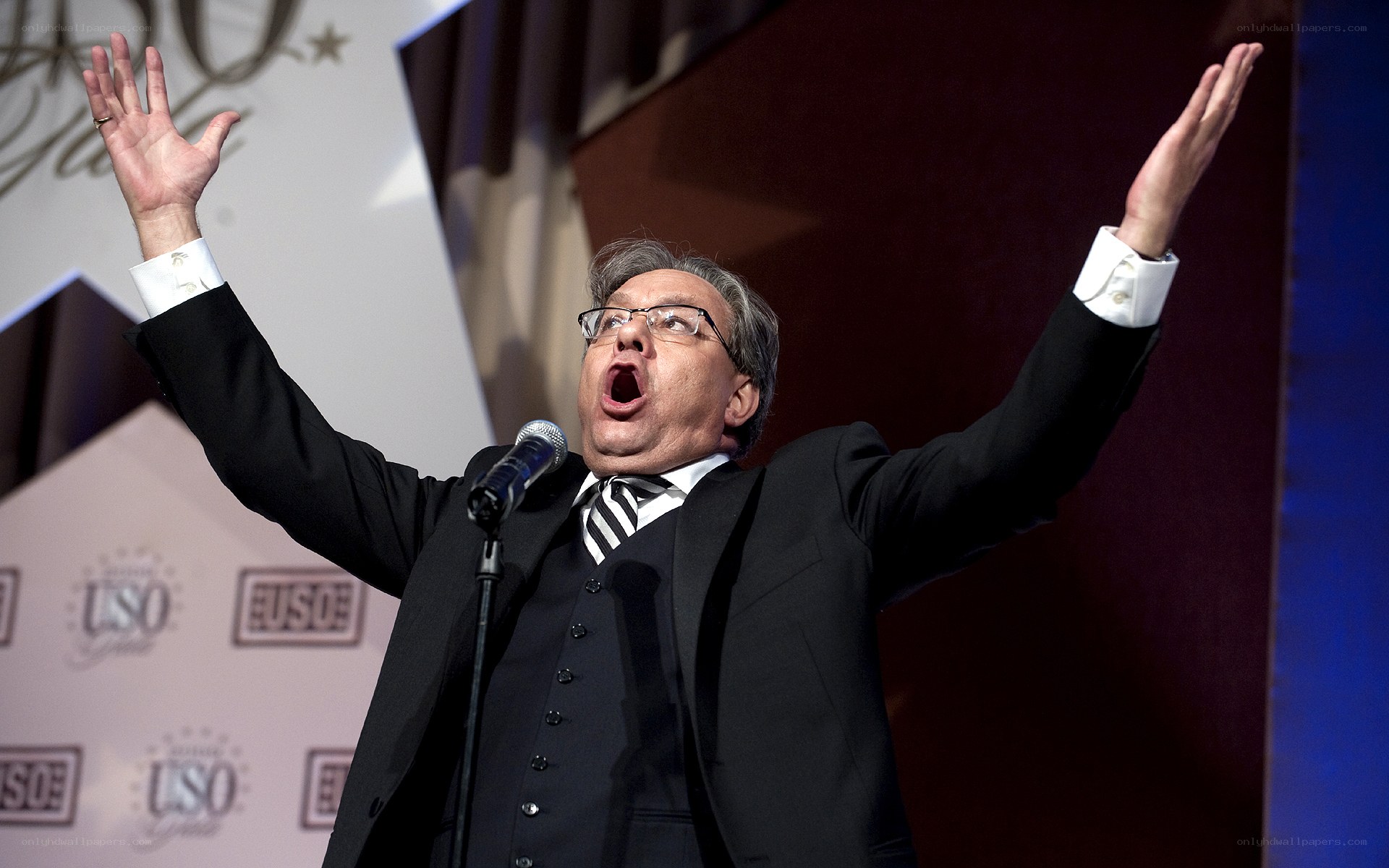 Man singing on stage with arms raised