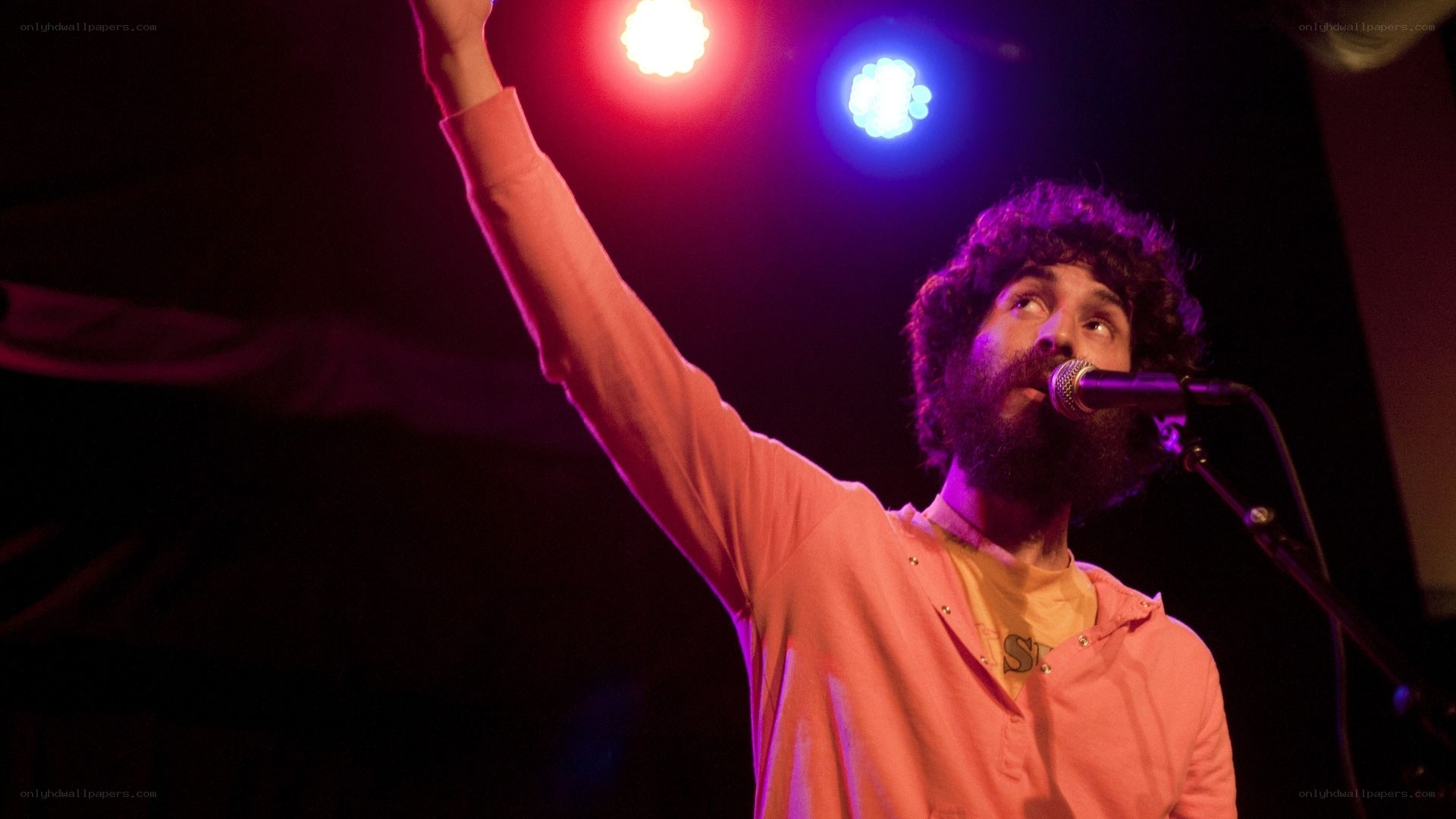 man singing on stage with raised arm