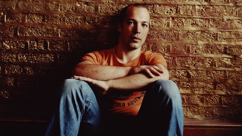 man sitting against brick wall