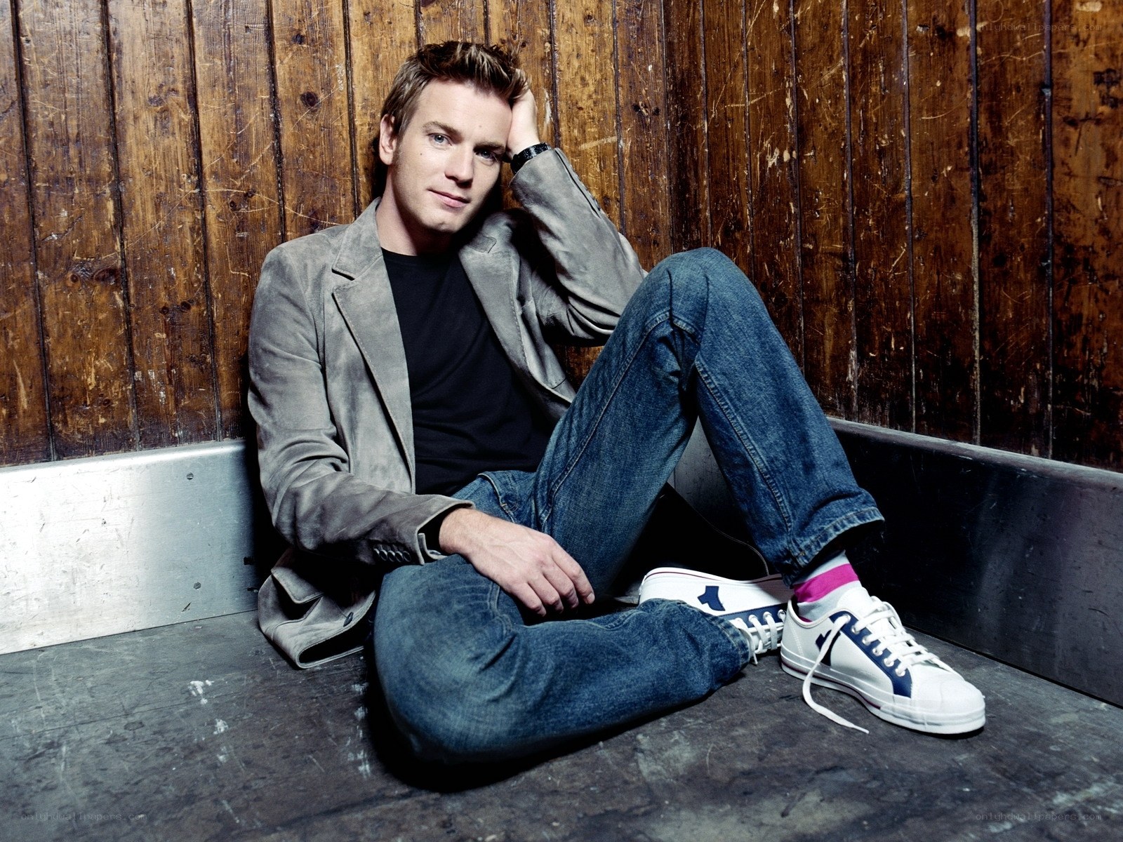 man sitting against wooden wall