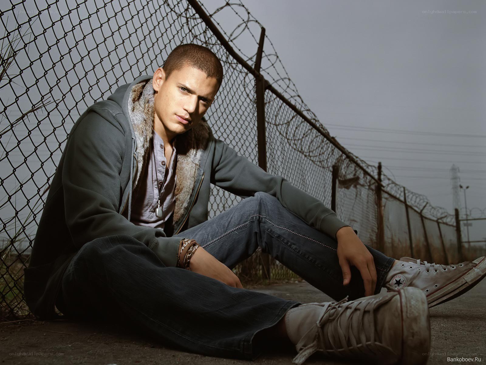 man sitting by fence