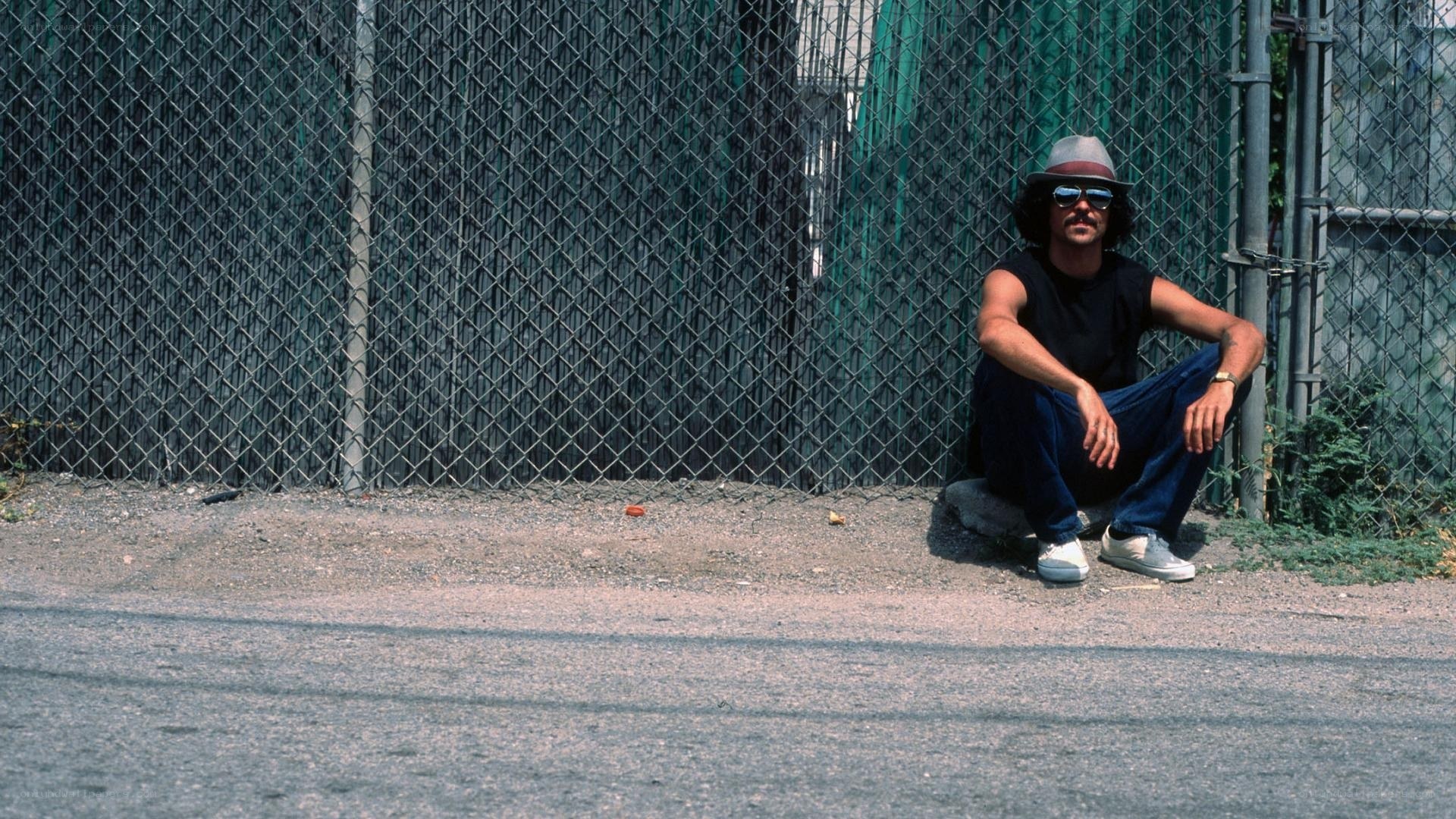 man sitting by fence