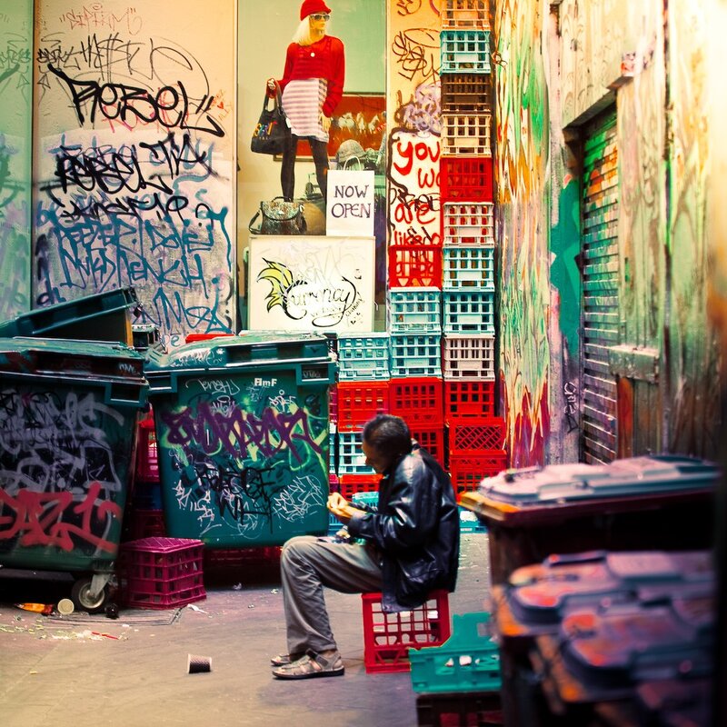 Man sitting in a graffiti alley