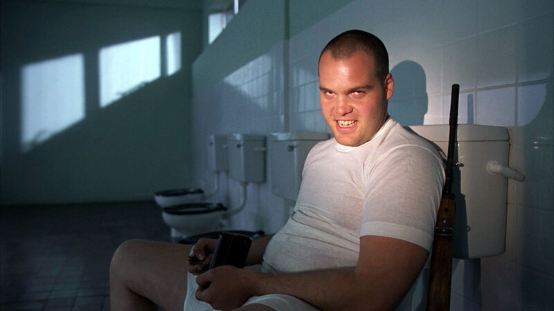 man sitting in bathroom with rifle