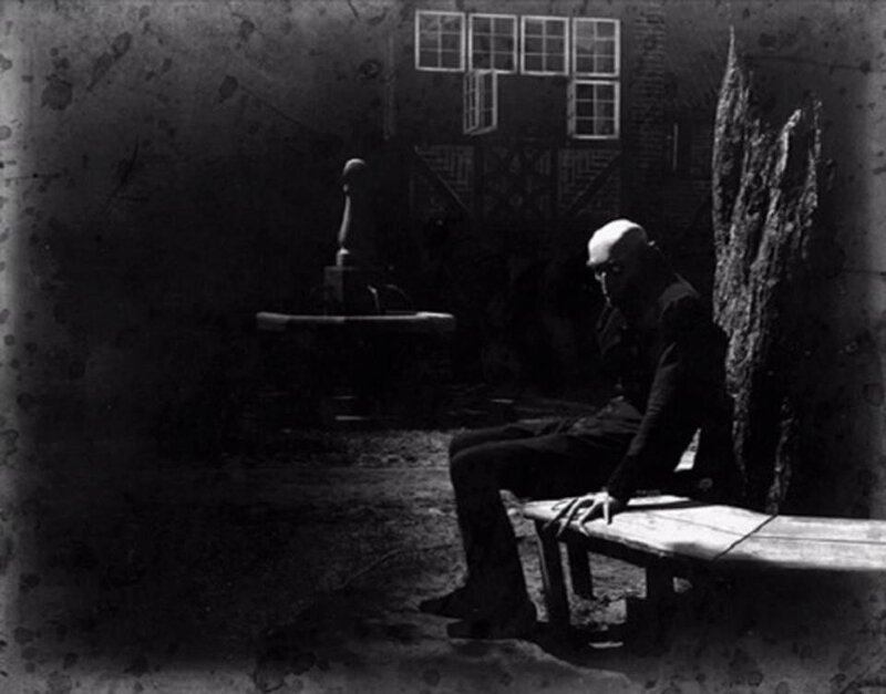man sitting in dark courtyard
