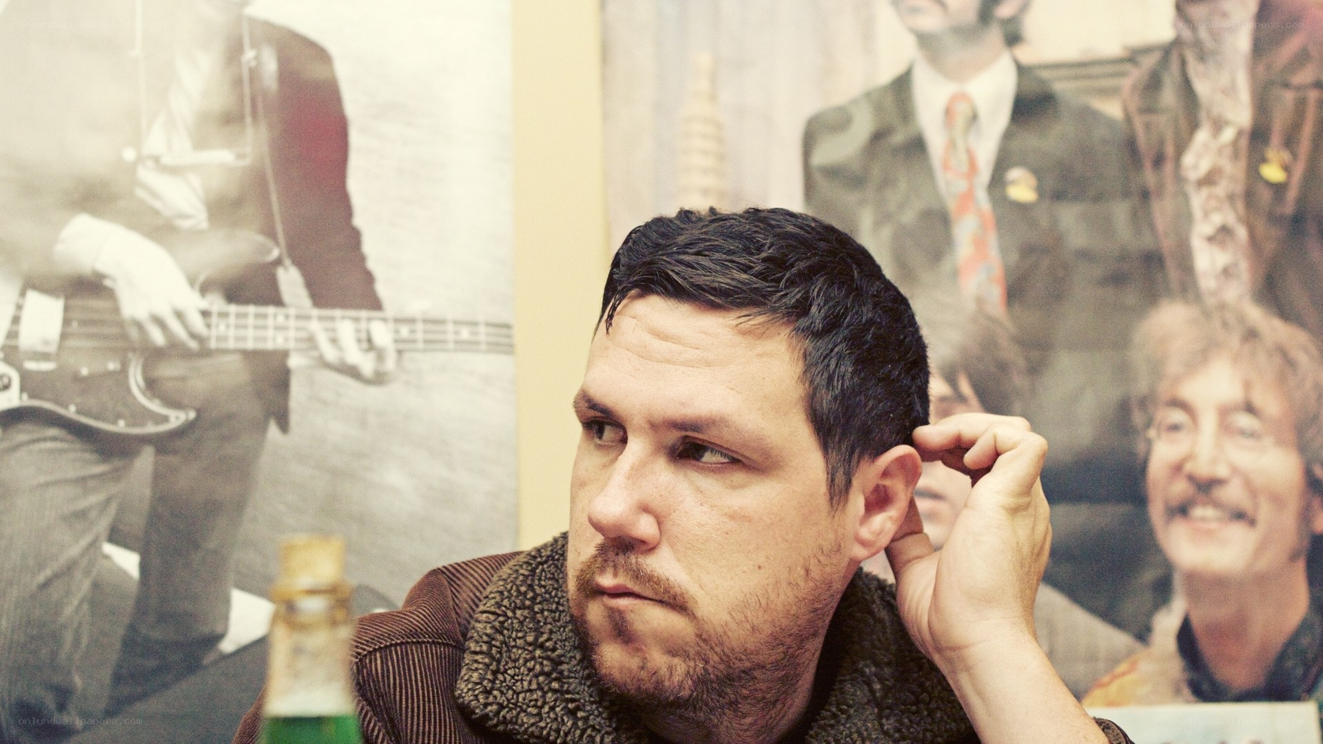 man sitting in front of band poster