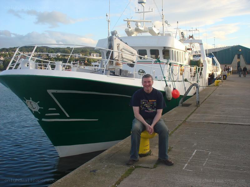 Man sitting on a dock by a boat