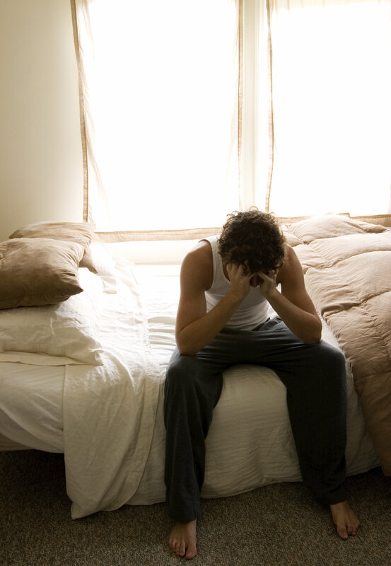 man sitting on bed in distress
