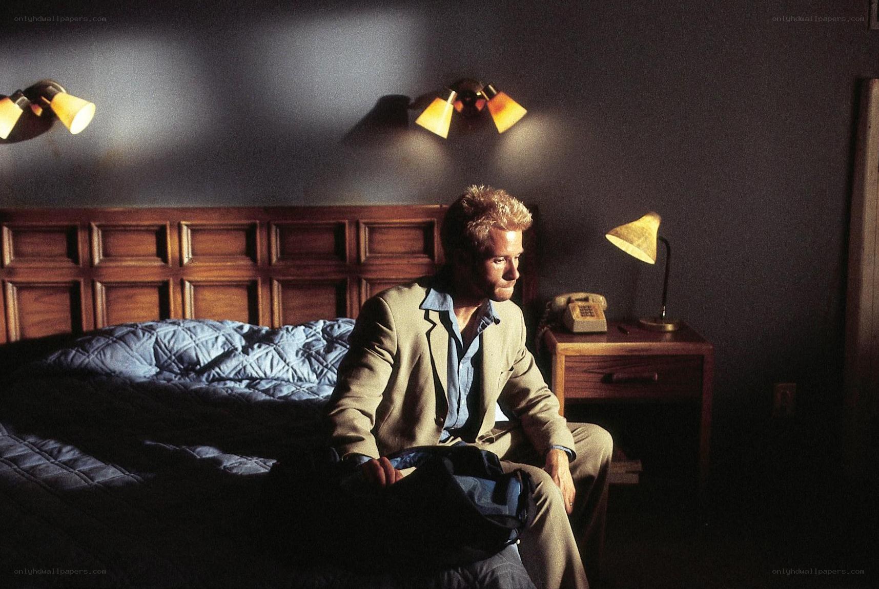 man sitting on bed in hotel room