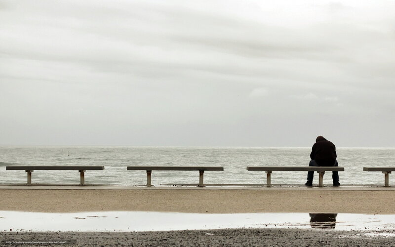 Man sitting on bench by sea
