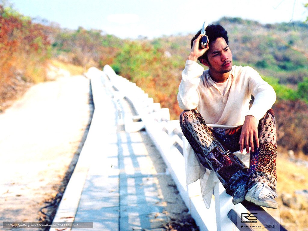 man sitting on bridge railing