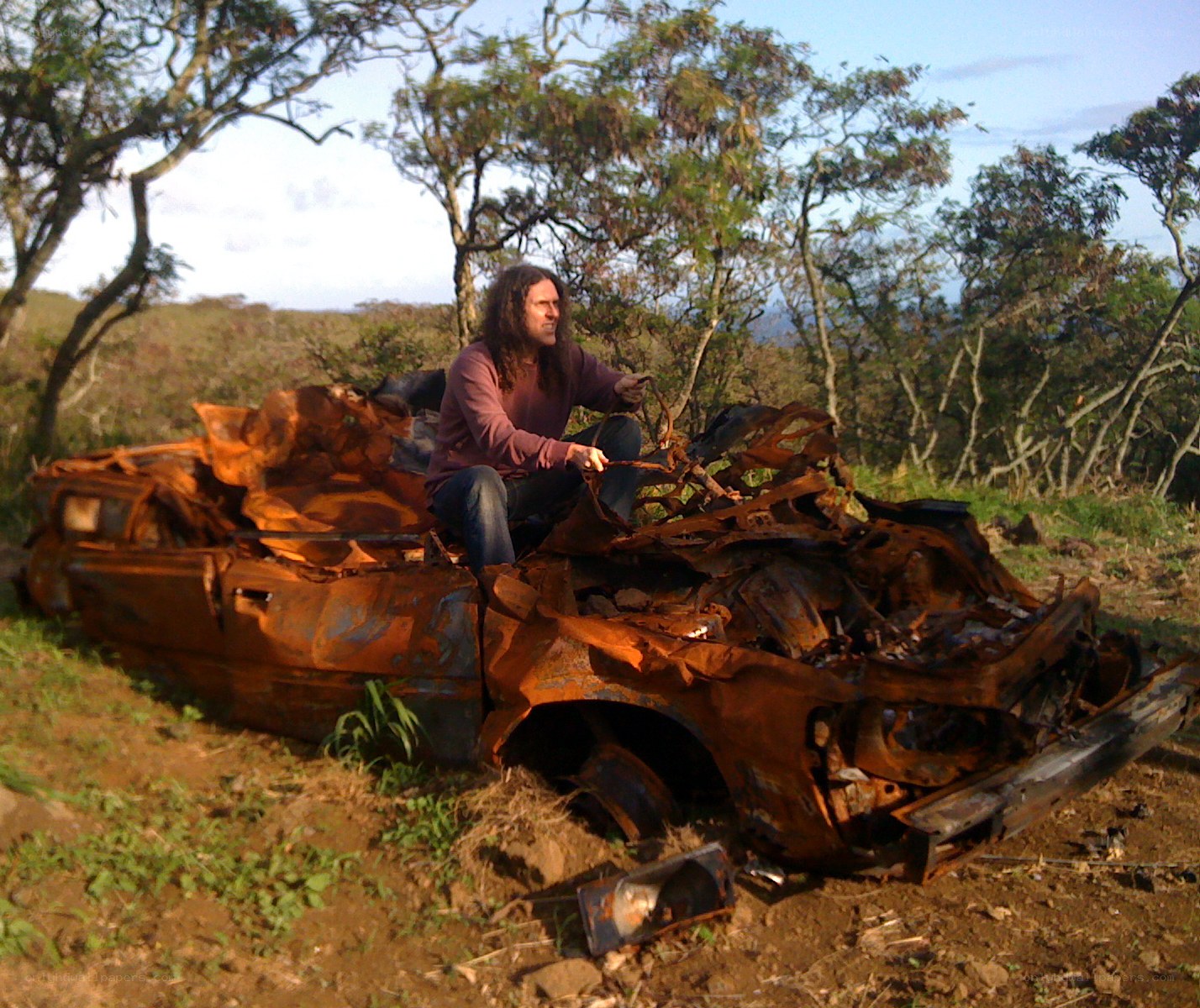 man sitting on car wreckage